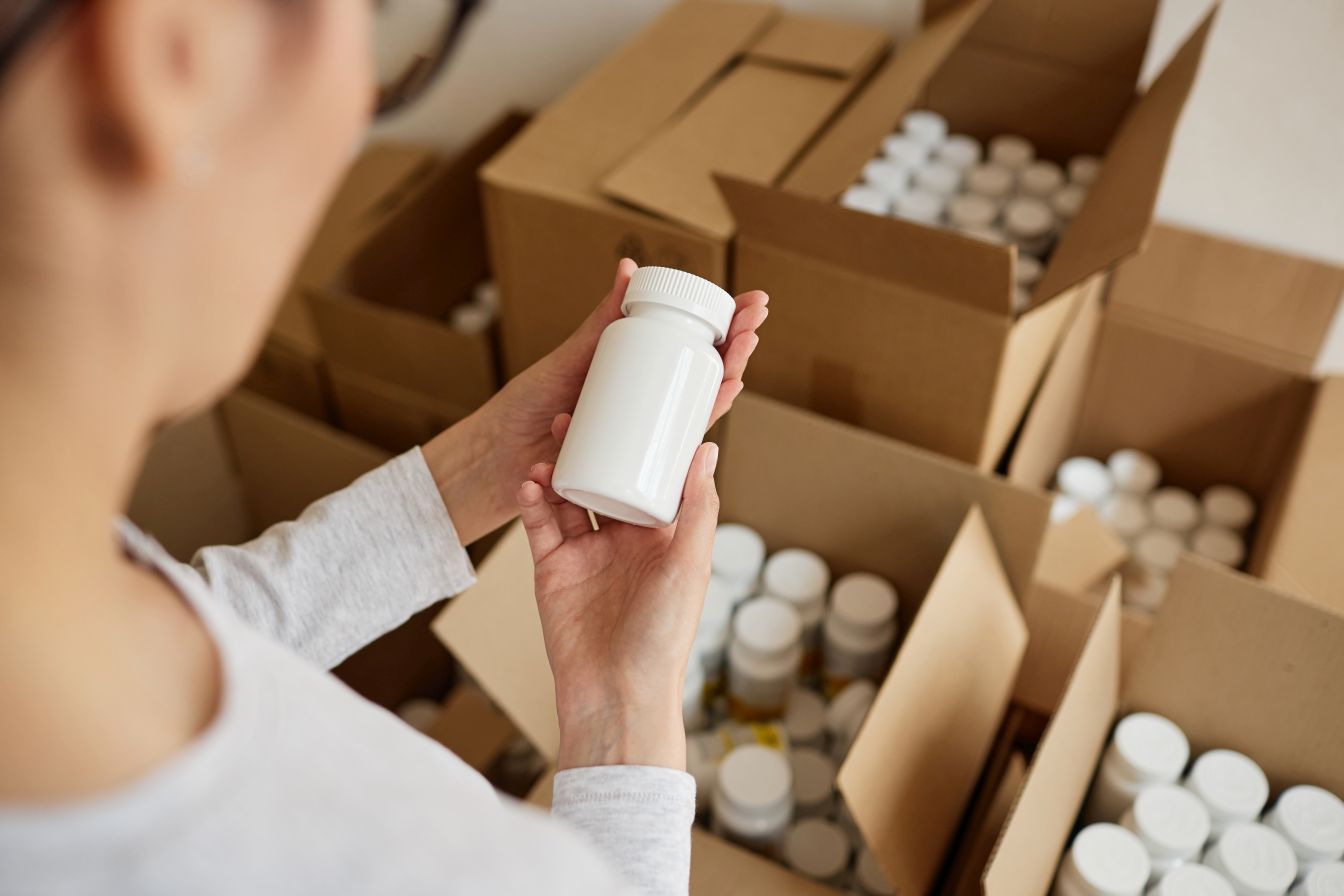 Quality control technician inspecting finished supplement bottles under GMP standards